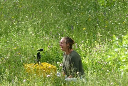 picture of person talking online in a meadow, laughing