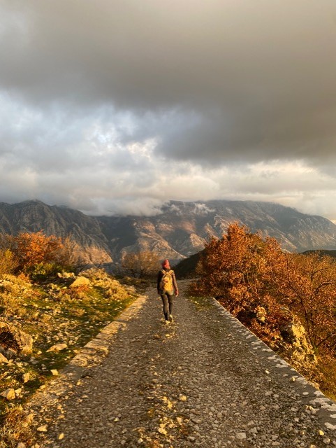 picture of person walking away from the camera in the mountains in Autumn