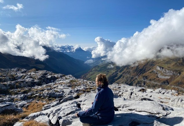 picture of person sitting high in the mountains above the clouds