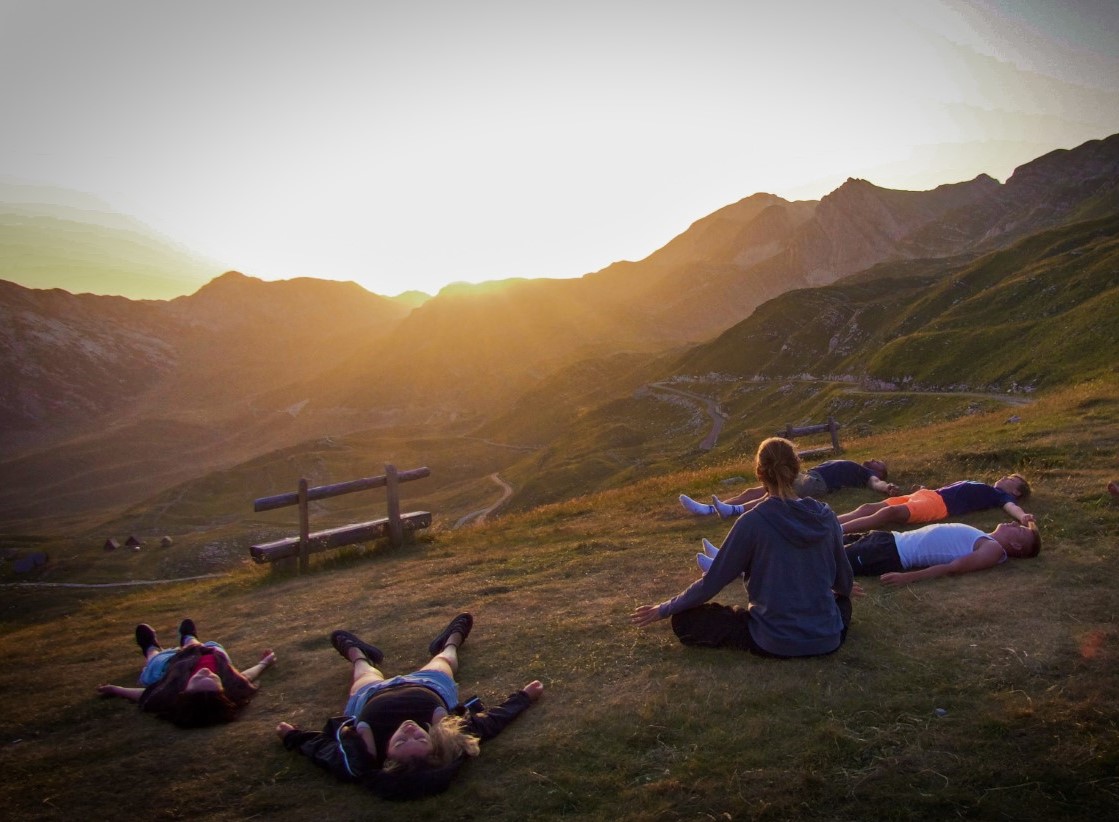 a group of people lying on a hill watching the sunset